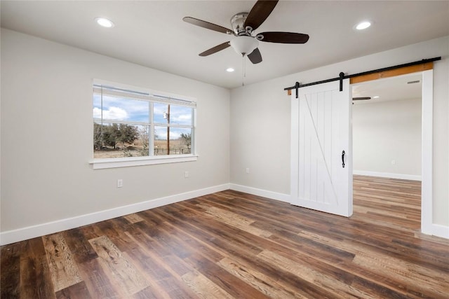 917 County Road 664, Devine, TX 78016 - unfurnished bedroom with a barn door, baseboards, wood finished floors, recessed lighting, and ceiling fan