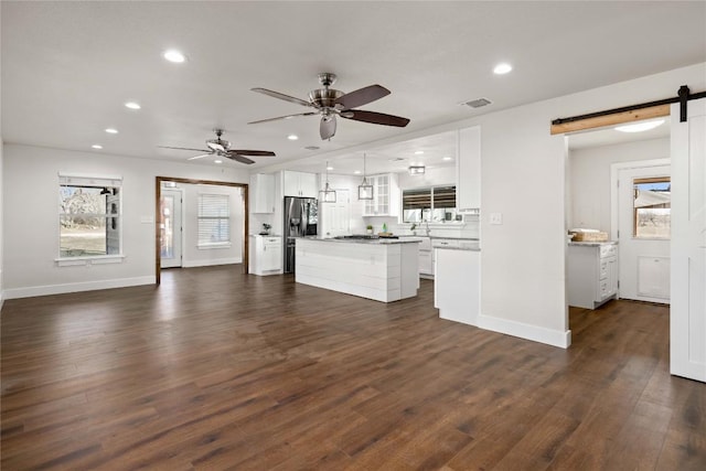 917 County Road 664, Devine, TX 78016 - unfurnished living room featuring a barn door, recessed lighting, baseboards, dark wood-style flooring, and ceiling fan