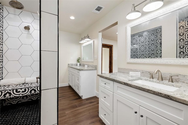 917 County Road 664, Devine, TX 78016 - bathroom with wood finished floors, two vanities, recessed lighting, and tiled shower