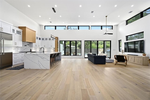 kitchen with a spacious island, visible vents, open floor plan, light wood-type flooring, and built in fridge