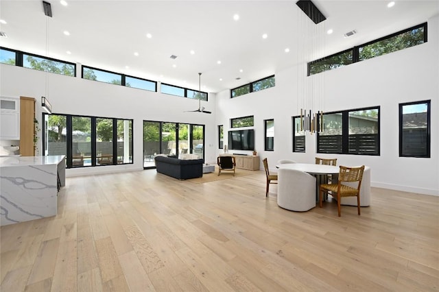 dining area with light wood finished floors, visible vents, baseboards, recessed lighting, and a high ceiling