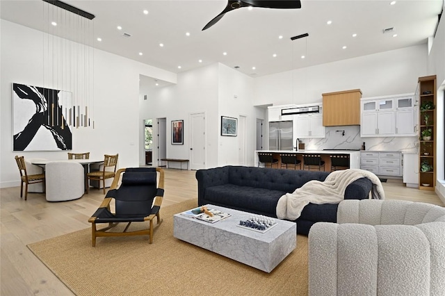 living area featuring visible vents, a high ceiling, recessed lighting, ceiling fan, and light wood-type flooring