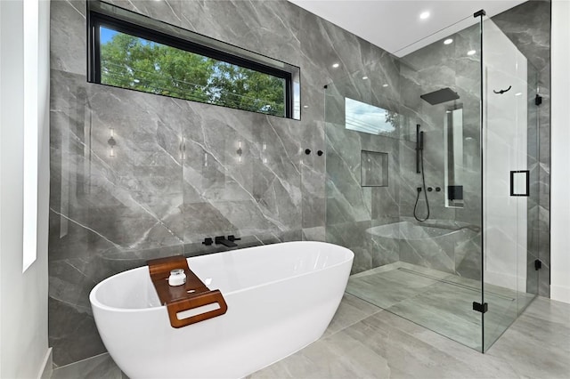 full bathroom featuring tile walls, marble finish floor, a marble finish shower, and a freestanding bath