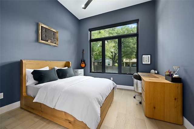 bedroom featuring a ceiling fan, vaulted ceiling, baseboards, and light wood-type flooring