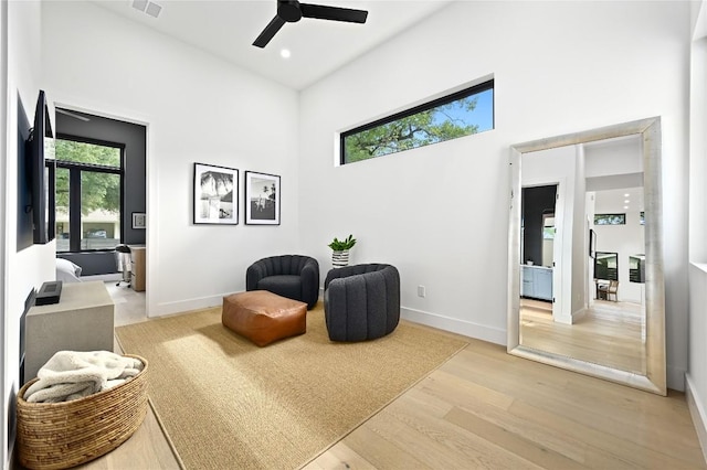 living area featuring baseboards, plenty of natural light, ceiling fan, and light wood finished floors