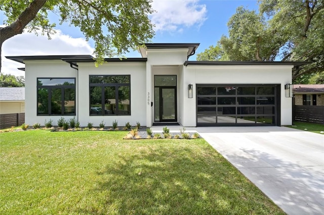 contemporary home featuring concrete driveway, stucco siding, a garage, and a front lawn