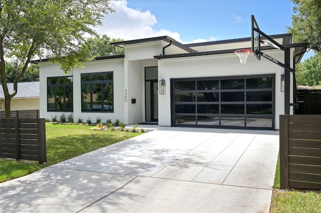 view of front of house featuring stucco siding, driveway, a front lawn, fence, and a garage