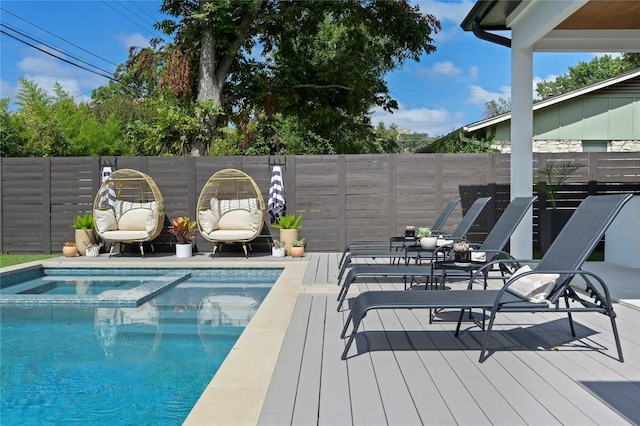 view of swimming pool with a pool with connected hot tub, a deck, and fence