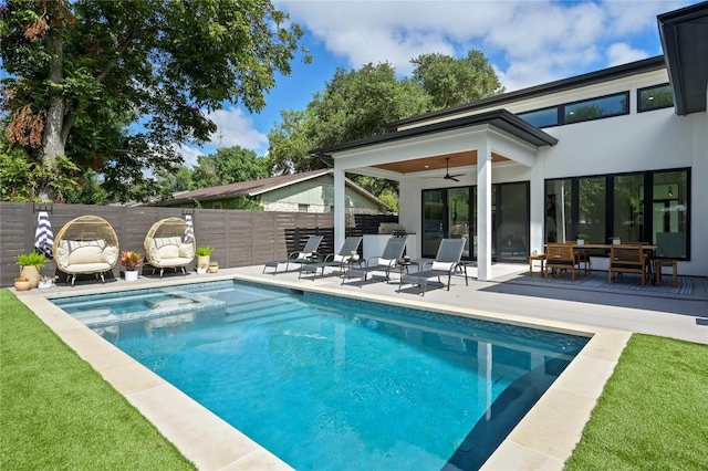 view of pool with a ceiling fan, a patio, fence, and a pool with connected hot tub