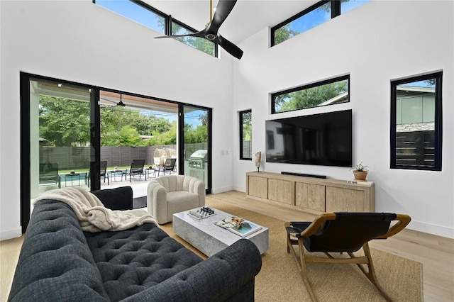 living room with baseboards, a high ceiling, a ceiling fan, and wood finished floors