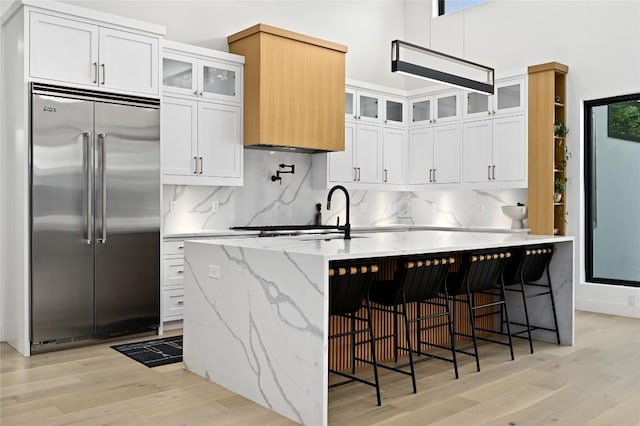 kitchen featuring tasteful backsplash, white cabinets, light wood-style floors, and stainless steel built in fridge