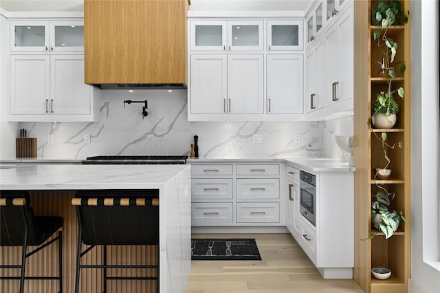 kitchen featuring glass insert cabinets, backsplash, and white cabinets