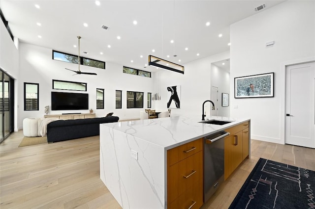 kitchen with visible vents, a large island with sink, a sink, modern cabinets, and brown cabinets