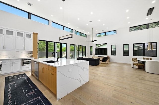 kitchen featuring visible vents, light wood-type flooring, a sink, stainless steel dishwasher, and open floor plan