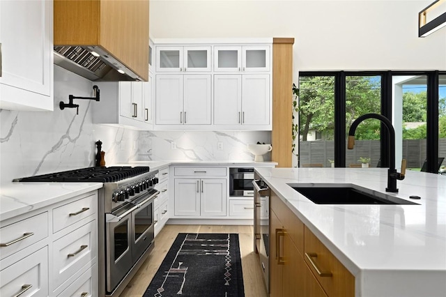 kitchen with white cabinetry, double oven range, light wood-type flooring, and a sink