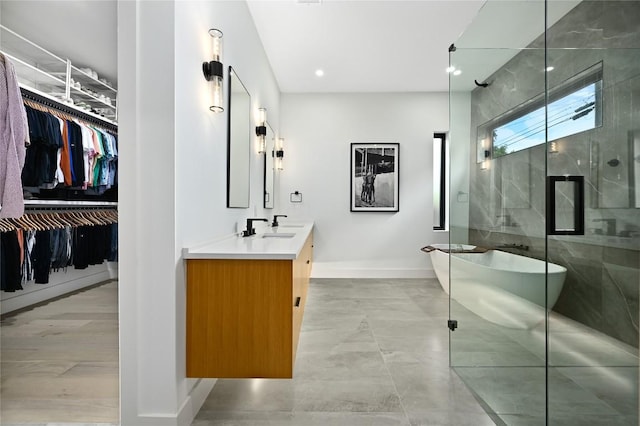 full bathroom with a freestanding tub, a walk in closet, a stall shower, baseboards, and vanity