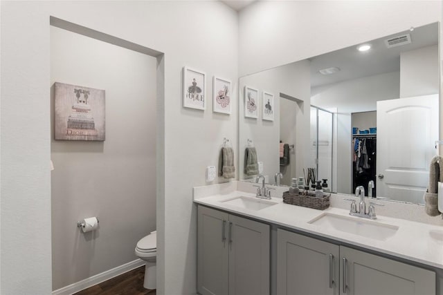 full bath featuring double vanity, visible vents, toilet, and a sink