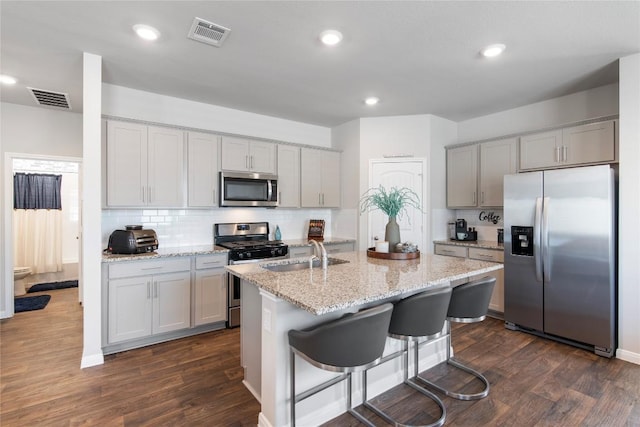 kitchen with visible vents, a sink, backsplash, dark wood-style floors, and appliances with stainless steel finishes