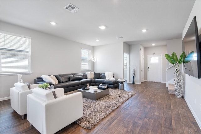 living area with dark wood finished floors, visible vents, a healthy amount of sunlight, and recessed lighting