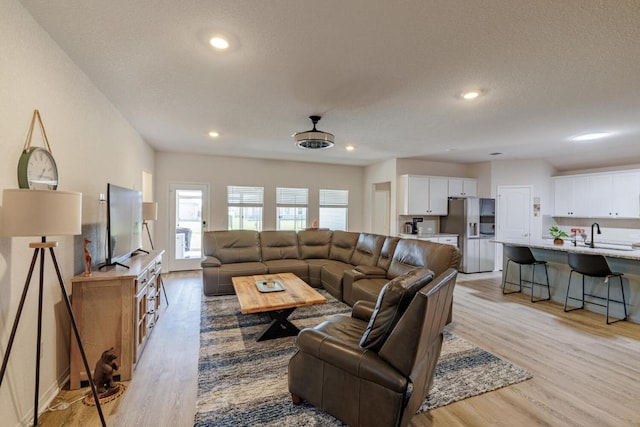 living room with recessed lighting, light wood-style floors, and a textured ceiling