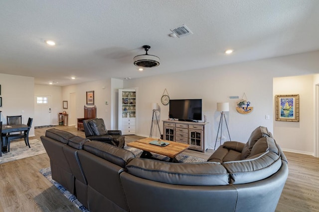 living area with recessed lighting, visible vents, light wood-style floors, and a textured ceiling