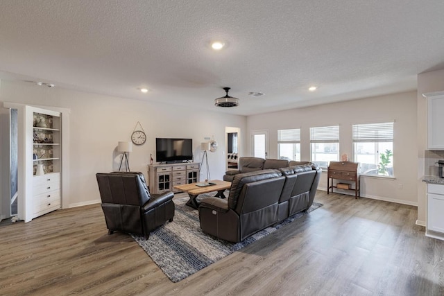 living room with baseboards, a textured ceiling, and wood finished floors