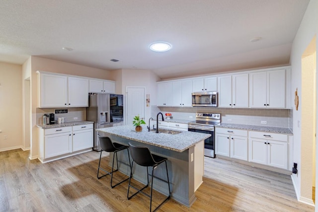 kitchen featuring a sink, stainless steel appliances, light wood finished floors, and white cabinetry