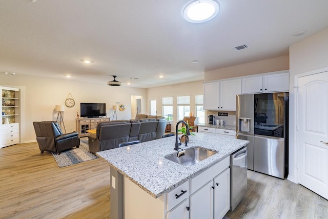 kitchen featuring visible vents, appliances with stainless steel finishes, light wood-style floors, white cabinetry, and a sink