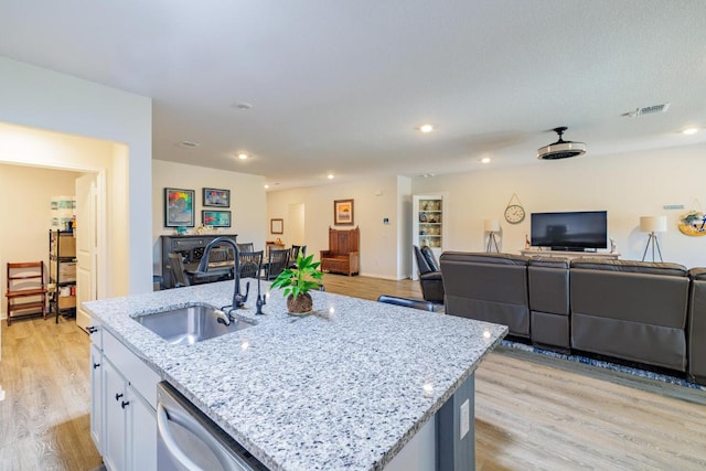 kitchen with a sink, light wood-style floors, open floor plan, and white cabinetry