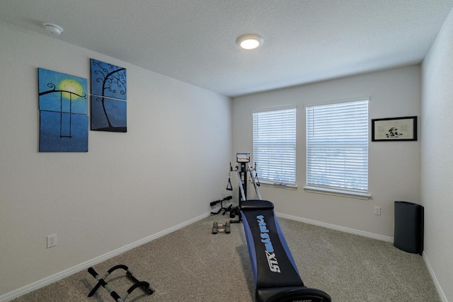 workout room with baseboards, carpet floors, and a textured ceiling