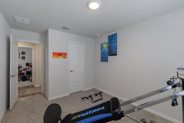 exercise room featuring visible vents, baseboards, and light colored carpet