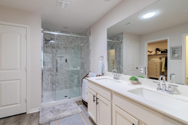 bathroom with a marble finish shower, wood finished floors, and a sink