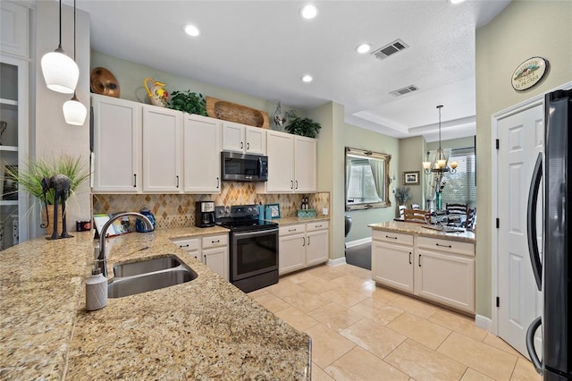 kitchen with a tray ceiling, a sink, white cabinets, appliances with stainless steel finishes, and tasteful backsplash