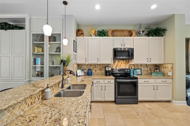 kitchen with backsplash, appliances with stainless steel finishes, white cabinetry, and a sink