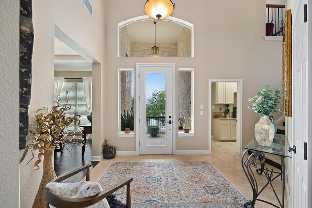 entryway with a high ceiling, visible vents, and a wealth of natural light