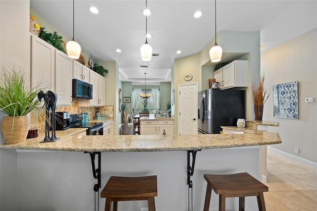 kitchen with black appliances, pendant lighting, light stone counters, white cabinets, and decorative backsplash