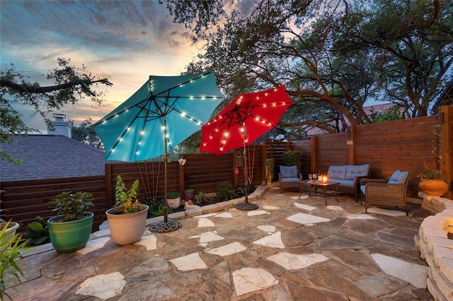 patio terrace at dusk with an outdoor living space and a fenced backyard