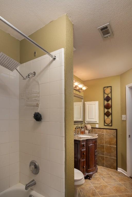 full bathroom featuring tile patterned flooring, visible vents, vanity, bathtub / shower combination, and a textured ceiling