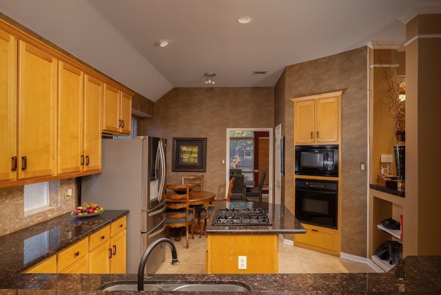 kitchen featuring visible vents, decorative backsplash, dark stone countertops, black appliances, and a sink