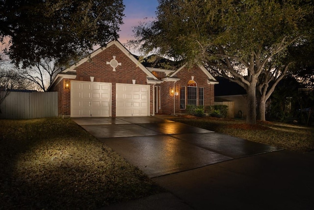 view of front of home featuring concrete driveway, an attached garage, fence, and brick siding