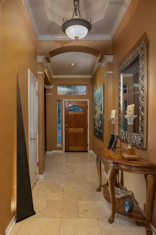 entrance foyer with arched walkways, baseboards, and ornamental molding