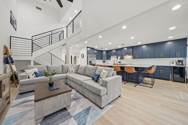 living area featuring visible vents, wine cooler, stairway, recessed lighting, and light wood-style floors