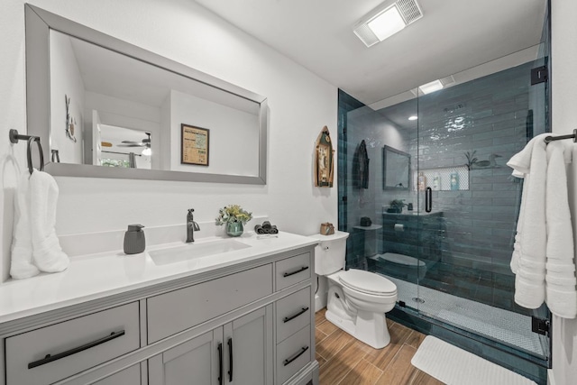 bathroom featuring vanity, visible vents, wood finish floors, a stall shower, and toilet