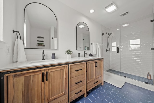 full bath featuring double vanity, visible vents, a stall shower, and a sink