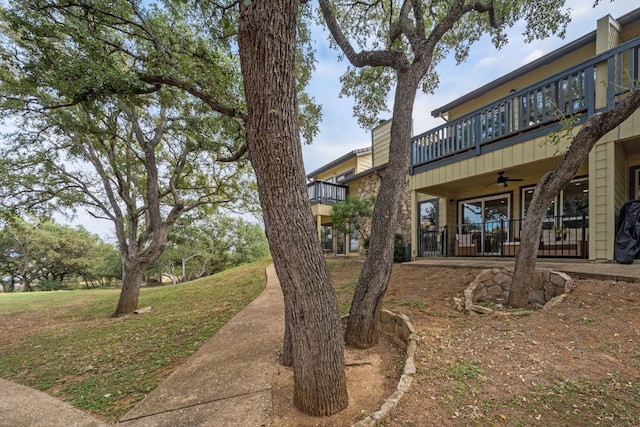 view of yard with a balcony and a ceiling fan