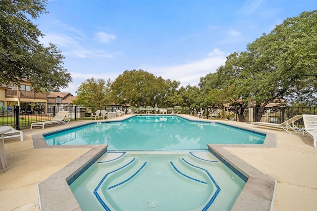 view of pool with a patio area, fence, and a pool with connected hot tub