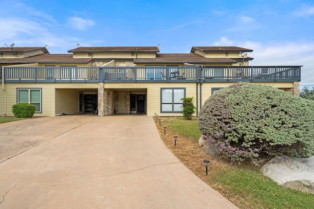 view of front facade with a wooden deck, a carport, and concrete driveway