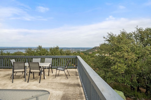 balcony featuring outdoor dining space and a water view