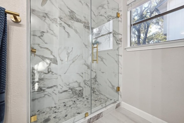 bathroom featuring a marble finish shower, marble finish floor, and baseboards