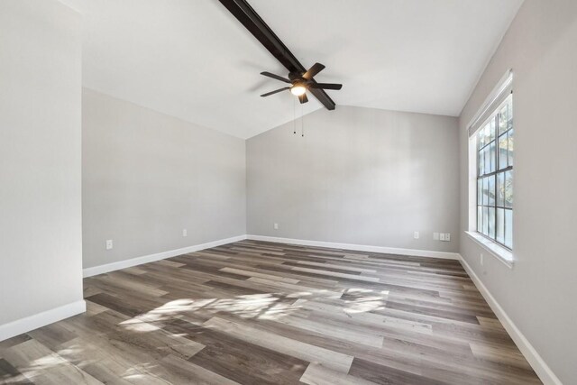 empty room with lofted ceiling with beams, wood finished floors, baseboards, and ceiling fan